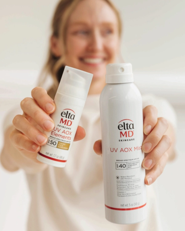 a woman holding two bottles of sunscreen
